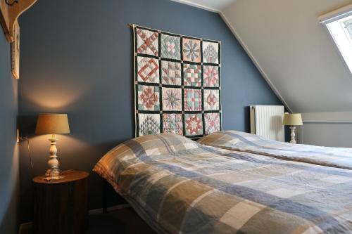 a bedroom with a bed and a quilt on the wall at De Fazant in Laren