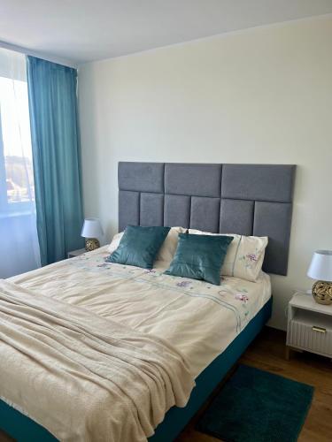 a large bed with a gray headboard in a bedroom at Apartament Emilia in Koszalin