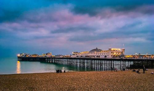 a pier with people on the beach next to the water at 'Bright Gem by the Sea' Premium Central 2 bedroom flat in Brighton & Hove