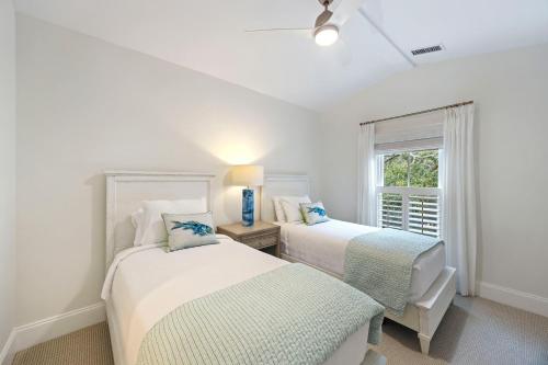 two beds in a white room with a window at 3026 Fairway One in Seabrook Island