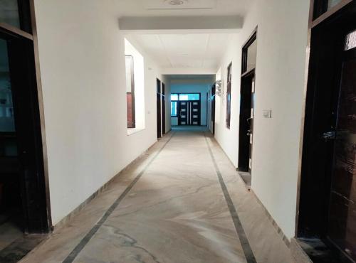 a hallway with white walls and a long hallway with black doors at Dev Palace in Nawai