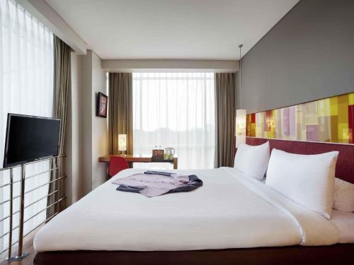 a hotel room with a large bed and a television at Ibis Styles Solo in Solo