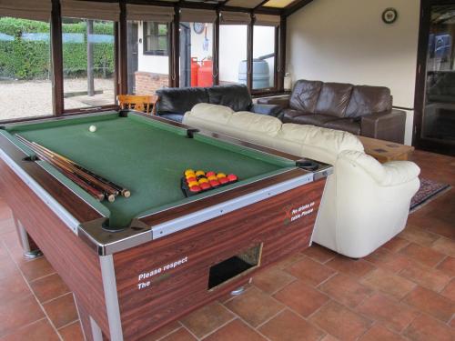a room with a pool table and a couch at Maytree Cottage in East Dereham