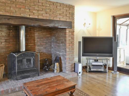 a living room with a fireplace with a tv at Maytree Cottage in East Dereham