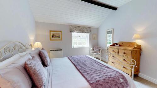a bedroom with a bed and a wooden dresser at Pant Glas in Penmaen-mawr