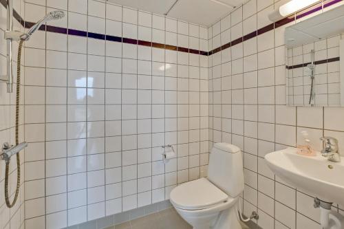 a white tiled bathroom with a toilet and a sink at Boeslunde Bed & Breakfast in Boeslunde