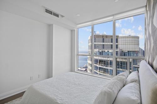 a bedroom with a bed and a large window at Panoramic Lakeview Resort Living 3BDR with Gym, Pool, Free parking in Toronto