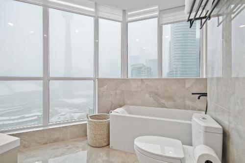 a bathroom with a tub and a toilet and windows at Panoramic Lakeview Resort Living 3BDR with Gym, Pool, Free parking in Toronto