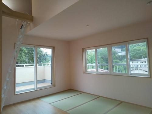 an empty room with three windows and a ladder at わんぱくポケット in Tenjin