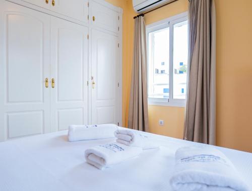 a bedroom with two towels on a bed with a window at La terraza de Albatros in La Isleta del Moro