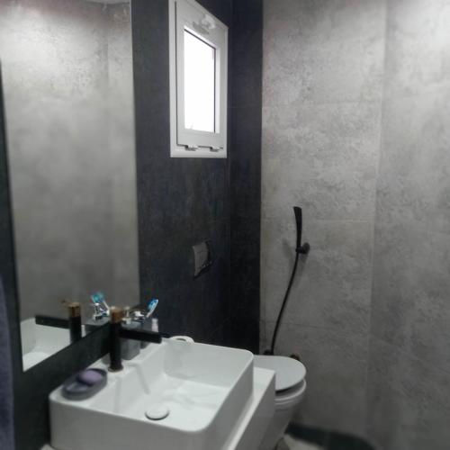a bathroom with a sink and a toilet and a window at Appartement Galaxy Hammamet in Hammamet Sud