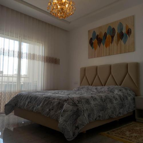 a bedroom with a bed and a chandelier at Appartement Galaxy Hammamet in Hammamet Sud