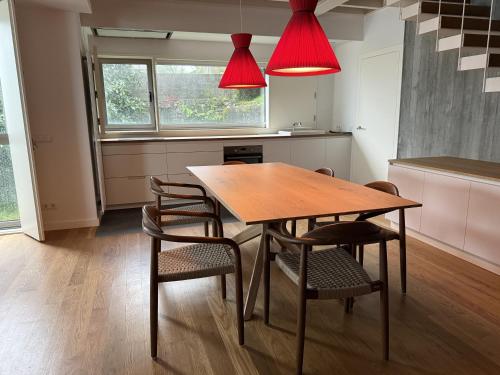 a kitchen with a wooden table with chairs and red lights at Lar do Mar in Beloso