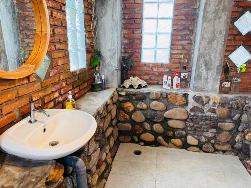 a bathroom with a sink and a brick wall at Lakey Views Sumbawa in Huu