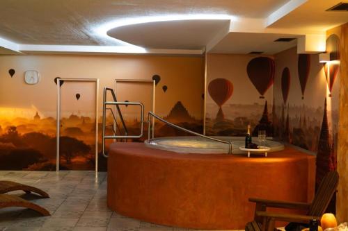 a hot tub in a room with a painting of hot air balloons at Wellness hotel - Viktorka, herecký dům in Česká Skalice