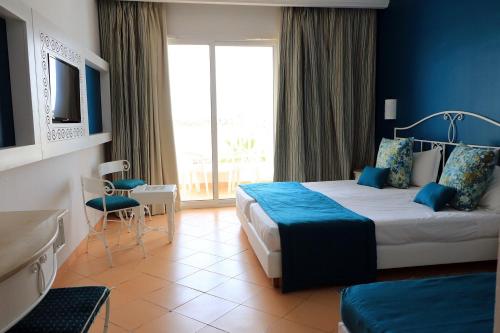 ein Hotelzimmer mit einem Bett und einem großen Fenster in der Unterkunft Riad Meninx in Bin Rhilouf