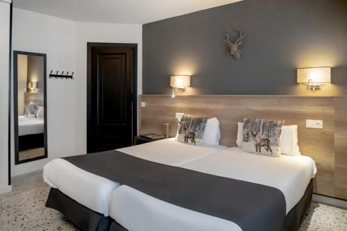 a hotel room with a large white bed and a mirror at Hotel Austria by Pierre & Vacances in Soldeu