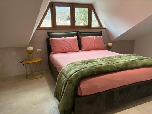 a bedroom with a bed with pink sheets and a window at Apartment Jasmina in Venzone