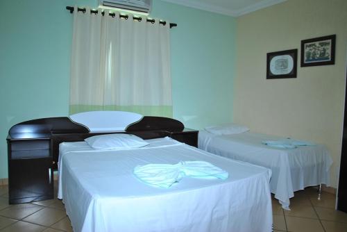 a hotel room with two beds with white sheets at Hotel Industrial Contagem in Contagem