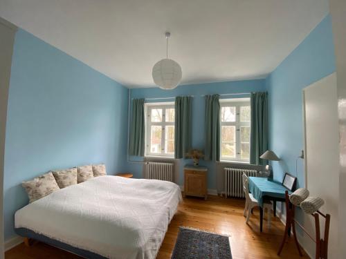 a bedroom with blue walls and a bed and a desk at The Old Parsonage in Søndersø
