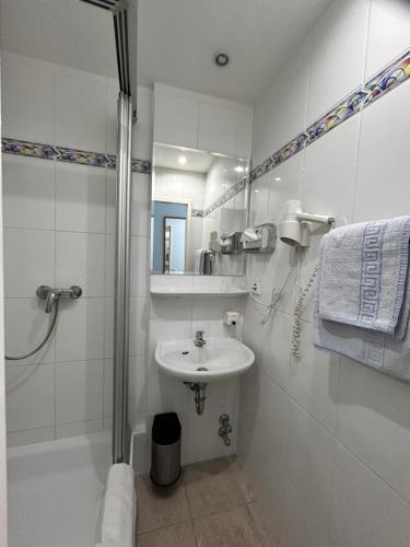 a white bathroom with a sink and a shower at Hotel Jägerhof in Wiesbaden
