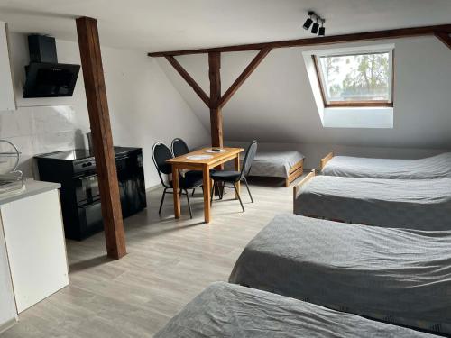 a room with two beds and a table and a kitchen at Gospoda Rycerska pod Grunwaldem in Grunwald