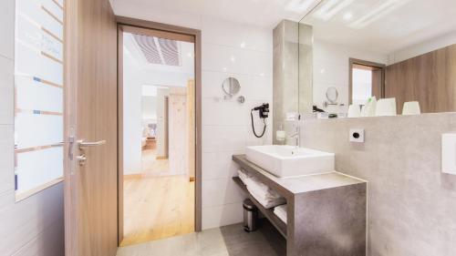 a bathroom with a sink and a mirror at Heuboden Hotel Heu.Loft Freiburg in Umkirch