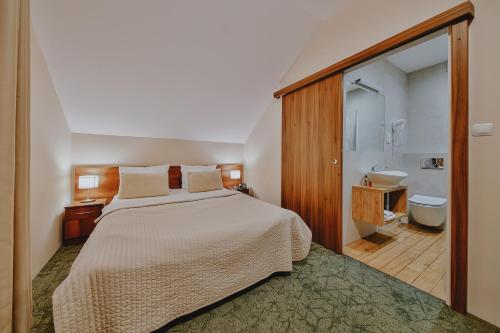 ein Schlafzimmer mit Bett und ein Badezimmer mit Waschbecken in der Unterkunft Hotel Kantoria in Tarnów
