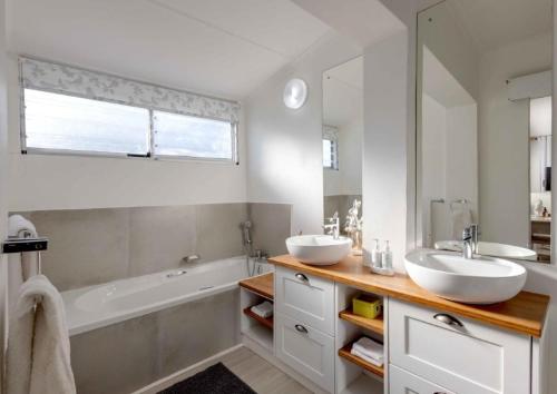 a bathroom with two sinks and a bath tub and a tubermott at Corner Delight at Onrust Beach in Hermanus