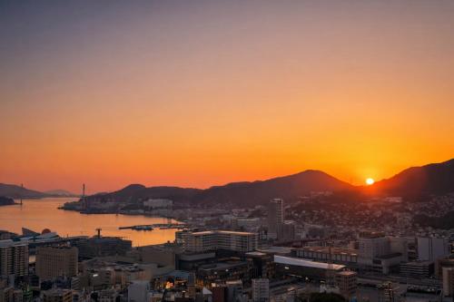 a city with the sunset in the background at Nagasaki Night View Terrace Entire Home -Inasayama Panorama稲佐山夜景テラス in Nagasaki