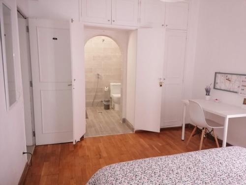 a white bedroom with a table and a bathroom at Vieira's House Suíte in Barreiro