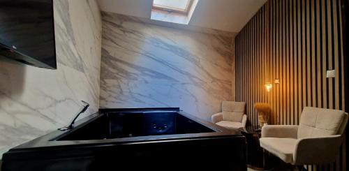 a bath tub in a room with two chairs at Junior Suites con Jacuzzi in Babilafuente