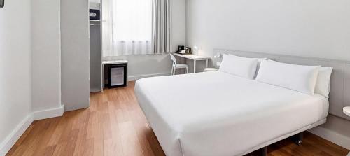 a bedroom with a large white bed and a table at B&B HOTEL Barcelona Mataro in Mataró