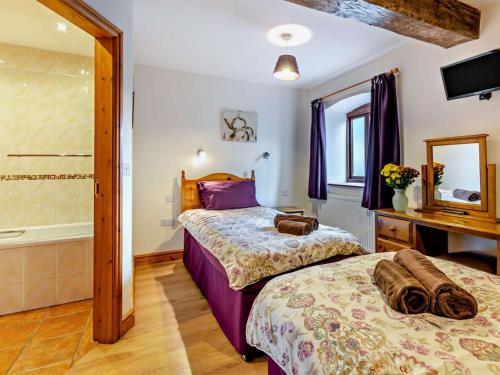 two beds in a bedroom with a tub and a mirror at 2 Bed in Ellesmere oc-94418 in Dodleston