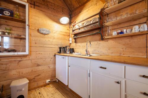 a kitchen with wooden walls and white cabinets and a sink at Valen Cabins in Reine in Reine