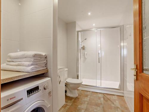 a white bathroom with a shower and a washing machine at 1 Bed in Lydney oc-73584 in Saint Briavels