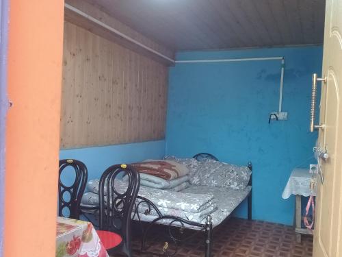 a small room with a bed and a blue wall at DSD Bomzon Homestay in Darjeeling