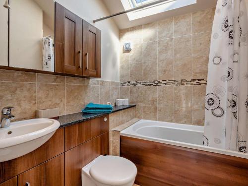 a bathroom with a tub and a toilet and a sink at 2 Bed in Blakeney oc-54765 in Awre