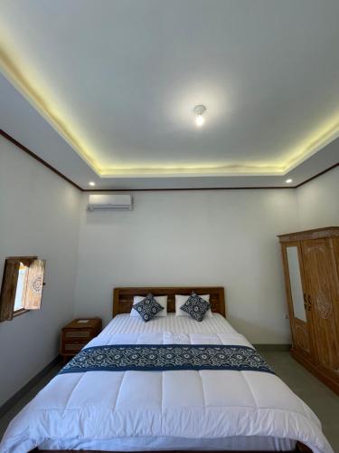 a bedroom with a white bed with blue pillows at Raditya Homestay in Mambat