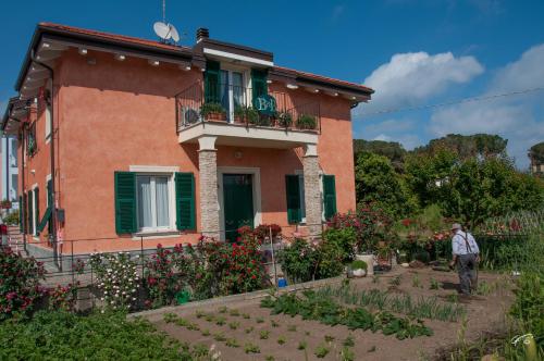 a man standing in front of a house with a garden at Guest House Arancia145 in Ceriale