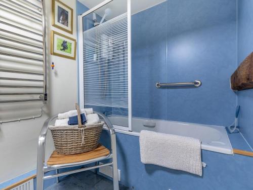 a blue bathroom with a tub and a basket on a chair at 2 Bed in Kidderminster oc-cc090 in Bayton