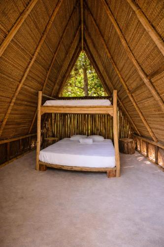 a bed in a straw tent with a window at Muluk Grove Lodge in Placencia