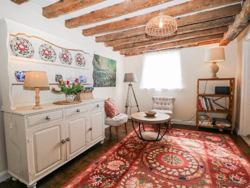 a living room with a table and a rug at Quince Cottage in Lewes