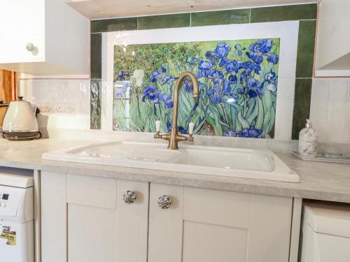 a kitchen sink with a painting on the wall at Quince Cottage in Lewes
