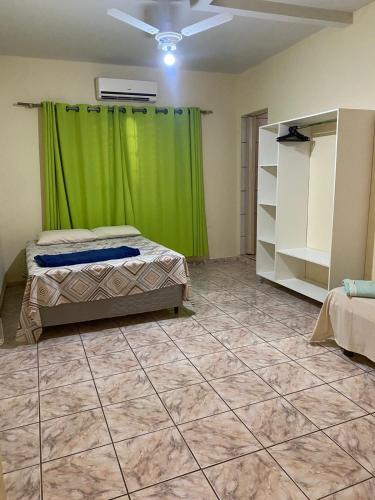 a bedroom with a green curtain and a tiled floor at Império Hotel in Costa Rica
