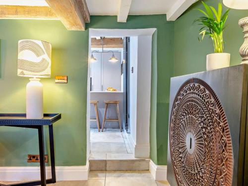 a hallway with green walls and a table with a chair at 3 Bed in Warwick oc-93887 in Kineton