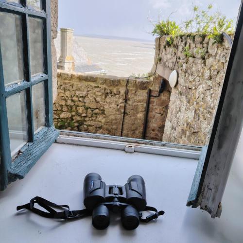 a pair of binoculars on the floor in front of a window at Chez Adèle, au pied de l'Abbaye in Le Mont Saint Michel