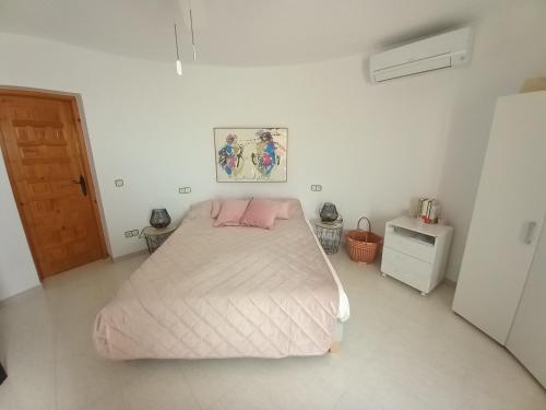 a white bedroom with a bed with a pink pillow at Marcolina, 2 in Alcalà de Xivert