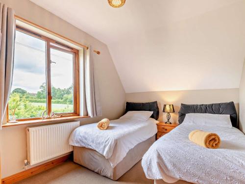 two beds in a room with a window at 3 Bed in Ledbury oc-77379 in Yatton