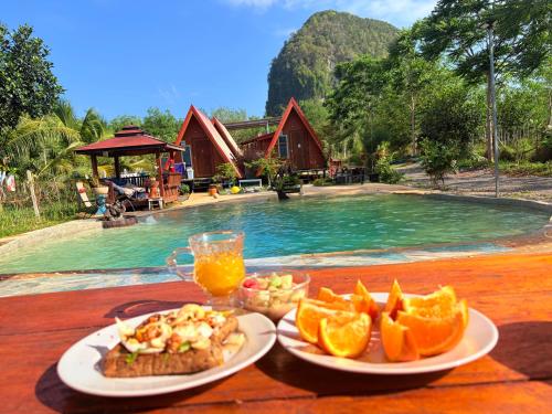 a table with a plate of food and a glass of orange juice at Thanya campsite Thailand in Ban Thai Thai